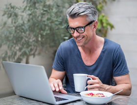 man on his laptop with a coffee sitting outside
