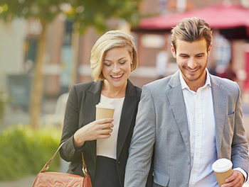 couple walking through a city with coffee cups