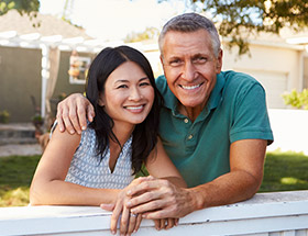 Rural Couple hugging at gate near their farmhouse