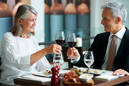 A mature man and woman raise a toast at a restaurant
