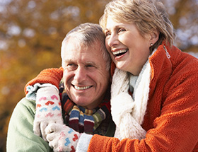 Elderly couple smiling and hugging