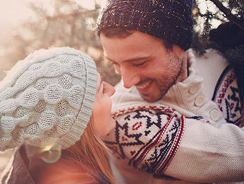 couple in beanies smiling at eachother at Christmas