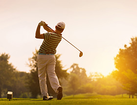 man playing golf at sunset