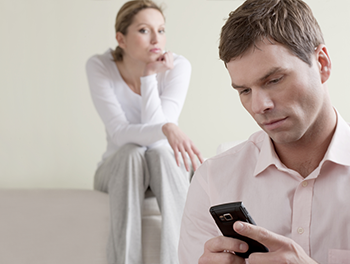 unhappy couple, man in the forefront on his phone