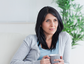 woman sitting and thinking with a mug in her hand