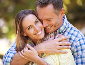 couple smiling and hugging outside