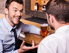 gay couple in a bar and chatting with beers