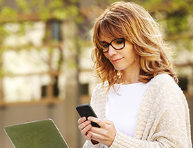 woman with glasses reading phone outside