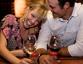 A man and a woman share a laugh over a glass of wine