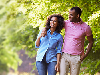 Black British couple walk arm in arm down a sunny country lane